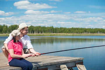 man helps a woman to fish in nature