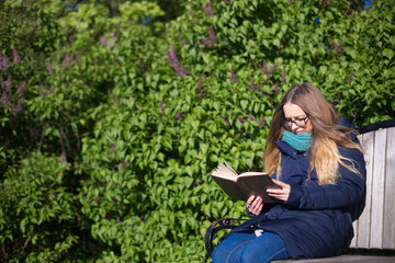 Girl reading a book in the park on the bench