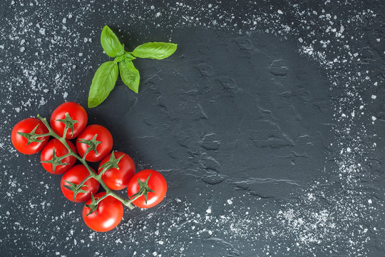 tomatoes and basil on black stone with salt