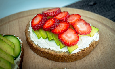 Delicious toast with avocado, strawberries, cheese cream, honey