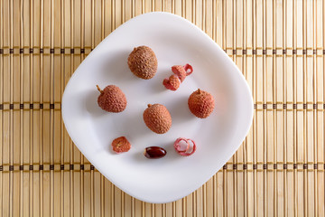 Group of the lychee, the lychee's seed and the lychee's peel on the white plate