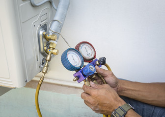 Technician is checking air conditioner with manometers, measuring equipment for filling air...
