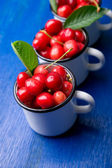 Cherry in enamel cup on blue wooden background. Healthy, summer fruit. Cherries...