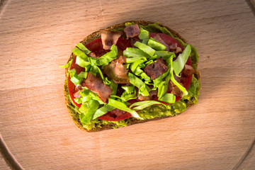 Delicious toast with avocado, tomato, bacon, salad. Top view