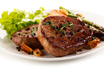 Grilled beef steaks with asparagus and carrots on white background 