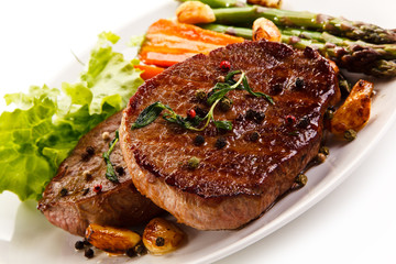 Grilled beef steaks with asparagus and carrots on white background 