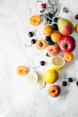 Summer fruits assorted on white marble background. Fresh raw food concept.