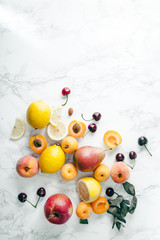 Summer fruits assorted on white marble background. Fresh raw food concept. Copy space