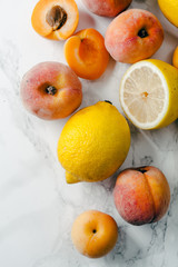 Yellow and orange summer fruits on white marble background. Color food collection concept.