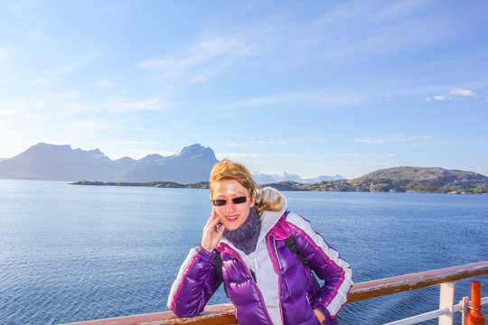 Norway cruise ship happy tourist enjoying trip to Northern Europe. Cruise on Norwegian Fjords. Caucasian woman on travel vacation ship. Spectacular landscapes of Lofoten Islands. Summer holidays.