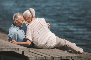 Happy senior couple hugging at wooden walkway at riverside