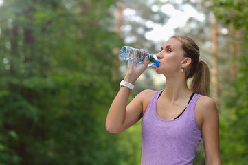 Young woman drinking water after jogging