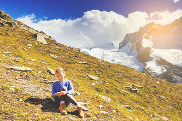 Naklejka premium Cute little girl wearing blue pullover and beige boots, resting in mountains, Switzerland