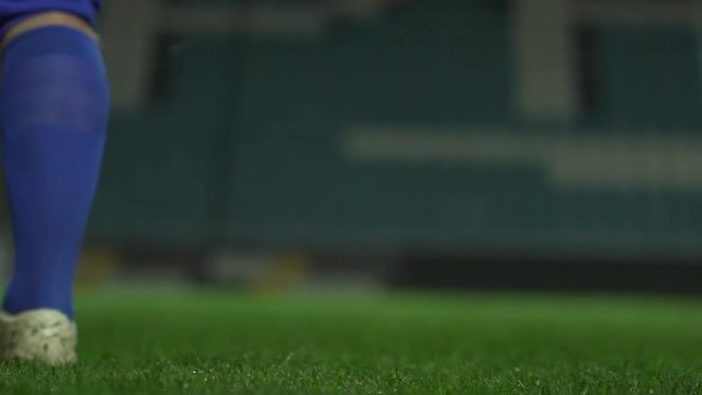 Close up footage in slowmotion. American football player fixing brown ball to kick it forward on stadium