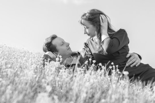 Affectionate young couple looking at each other on the lawn in the park. Love story. Black and white.