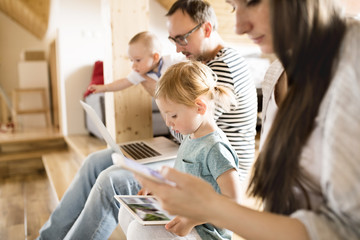 Young parents with little children and gadgets at home.