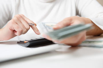 Fototapeta premium savings, finances, economy and home concept - close up of hands with calculator counting money and making notes at home