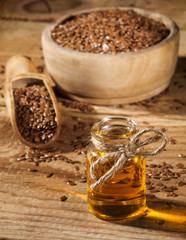 Linseed oil and bowl of linseeds on wooden background