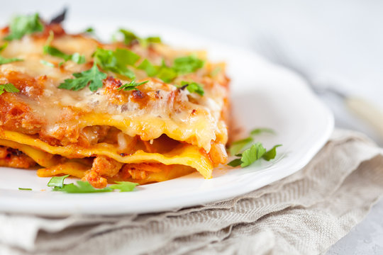 Piece of traditional Italian meat lasagna on a white plate.