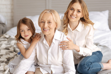 Obraz na płótnie Canvas Child and her mother having hands on grandmothers shoulders