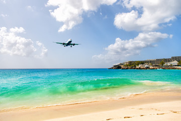 Fototapeta na wymiar Airplane landing above beautiful beach and sea