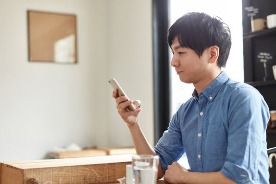 カフェで携帯電話を使う男性