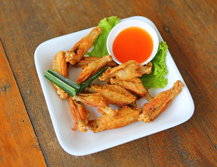 fried chicken wings with herb in white plate on wood.
