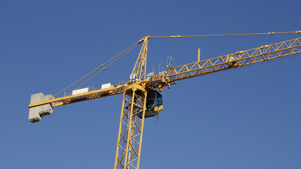 A generic yellow modern construction crane over a blue sky