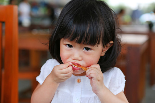 Portrait Of One Year Old And Eight Month Child, Baby Girl Eating A Chicken Wing.