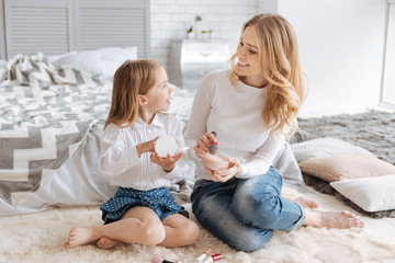 Young mother and her daughter discussing cosmetics