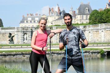 jeune couple pratiquant la marche nordique