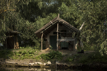Old wooden house on a channel in Danube Delta, Romania, in a sunny summer day