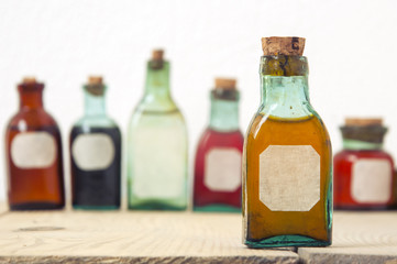 Mock up of small glass antique bottles with colored liquids. Selective focus. For the pharmacy, oil, cosmetics.