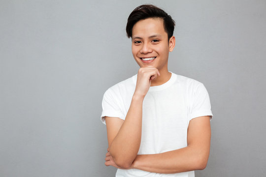 Handsome Young Asian Man Standing Over Grey Background