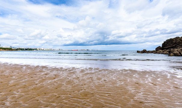 Atlantic sandy beach in Spain with city of Coruna background.