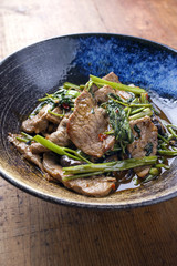 Traditional Stir Fried Thai Pad Nua with Morning Glory as close-up in a bowl
