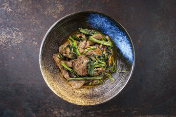 Traditional Stir Fried Thai Pad Nua with Morning Glory as close-up in a bowl