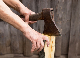 The old axe in the hands of an elderly person colitis firewood