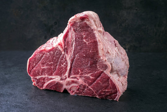 Raw dry aged Wagyu Porterhouse Steak as close-up on a black slate