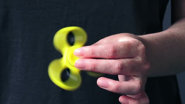 Yellow fidget spinner in female hand, selective focus