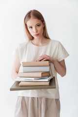 Serious blonde woman holding books. Looking at camera.