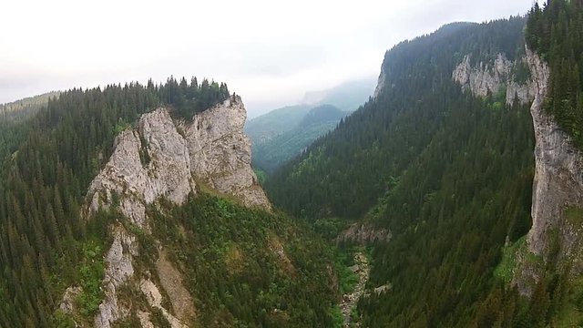 Flying towards spectacular  limestone shale conglomerate rocks  and coniferous trees , alpine landscape in the Zanoaga Gorge , Bucegi Natural Park , Carpathian Mountains, Romania, aerial view