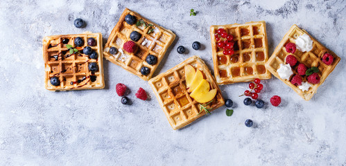 Homemade square belgian waffles with fresh ripe berries blueberry, raspberry, red currant, peach...