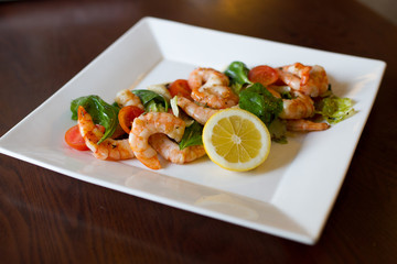 Shrimp salad with vegetables on white plate.