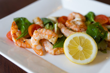 Shrimp salad with vegetables on white plate.