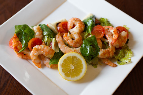 Shrimp salad with vegetables on white plate.