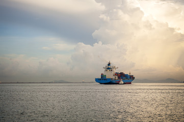 Cargo ship sailing away against sunrise