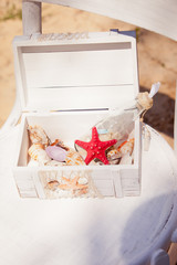 White box with seashells on dark blue fabric background. Decorative composition in marine style