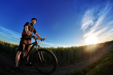 Fototapeta na wymiar Portrait of the cyclist with mountain bike on a background of blue sky with clouds.