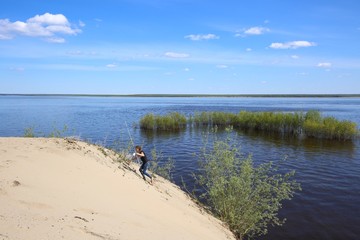 Young girl with a fishing rod on the river bank.